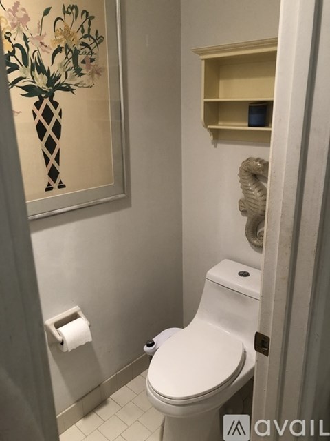 A white toilet in a bathroom with a pineapple picture on the wall.