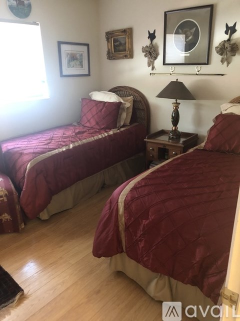Two twin beds with red bedspreads in a room.