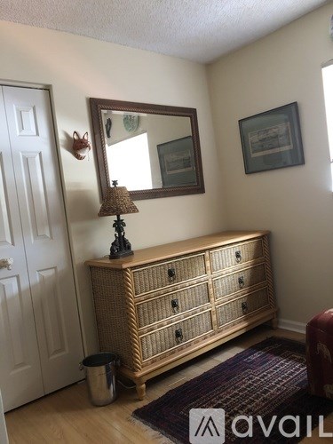 A wooden chest of drawers with a mirror above it and a lamp on top.