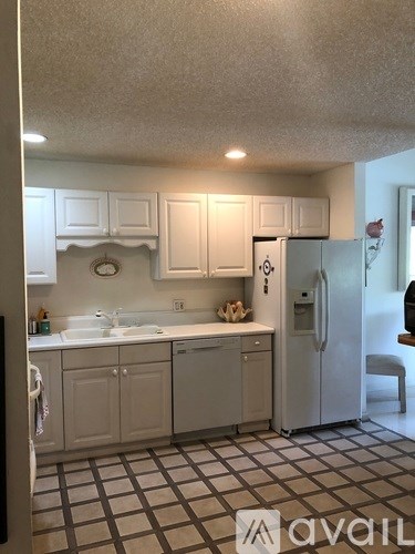 A kitchen with white cabinets and a white fridge.