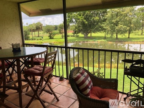 A balcony with a table and chairs overlooking a green field.