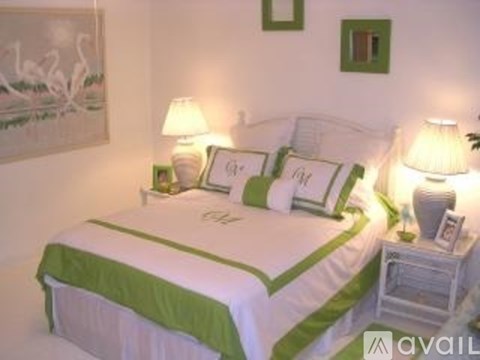 A bed with a green and white comforter and pillows is in the image.