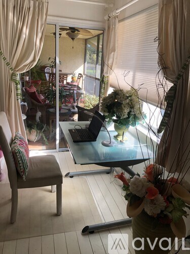 A room with a chair, a table, and a vase of flowers.