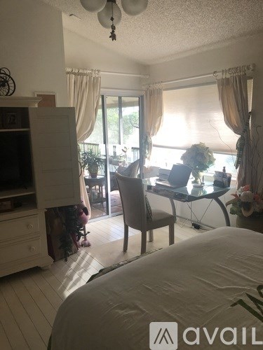 A bedroom with a bed, a desk with a chair, and a window with curtains.