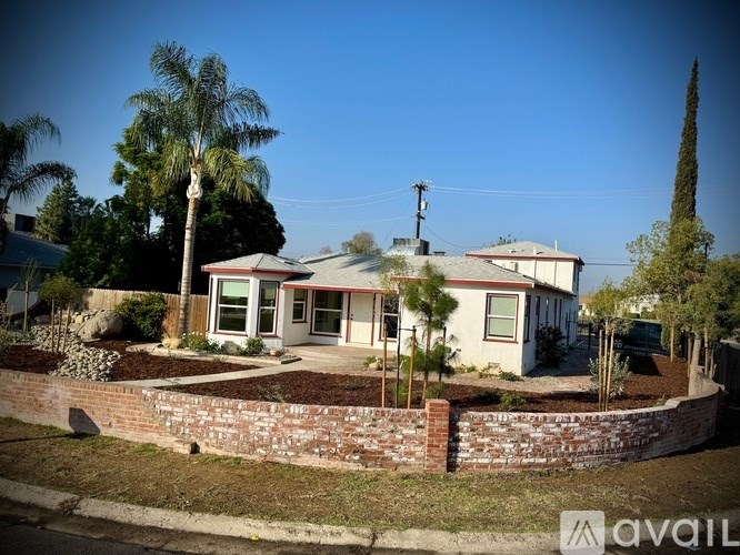 A house with a red roof and a brick wall in front.