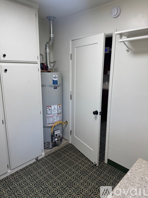A small utility room with a water heater and a ventilation pipe.