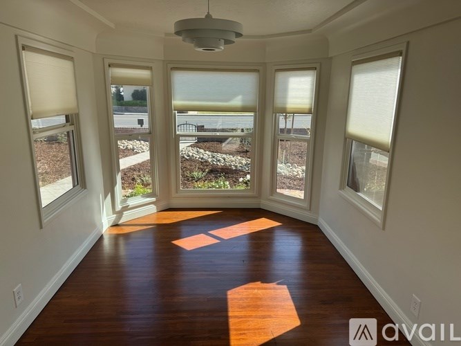 A room with wooden floors and large windows overlooking a garden.