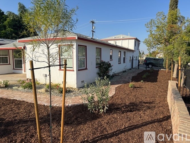 A white house with a red roof and a garden in front.