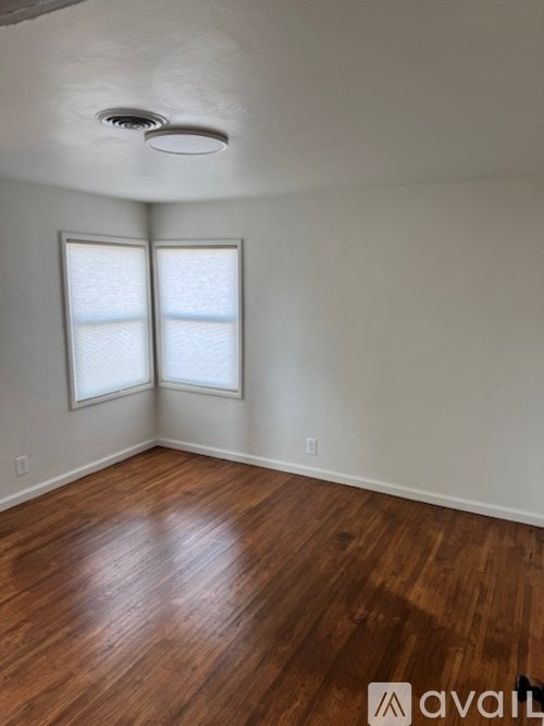 A room with wooden floors and two windows.