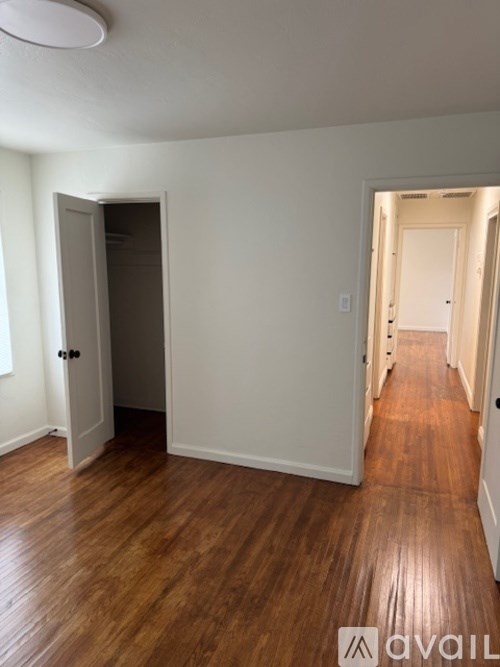 A room with wooden floors and two doors, one of which is open.