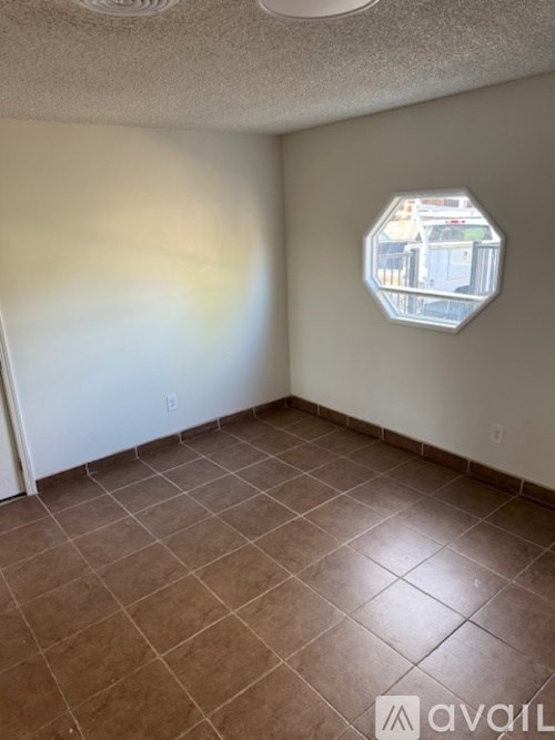 A room with brown tiles and a hexagonal mirror on the wall.