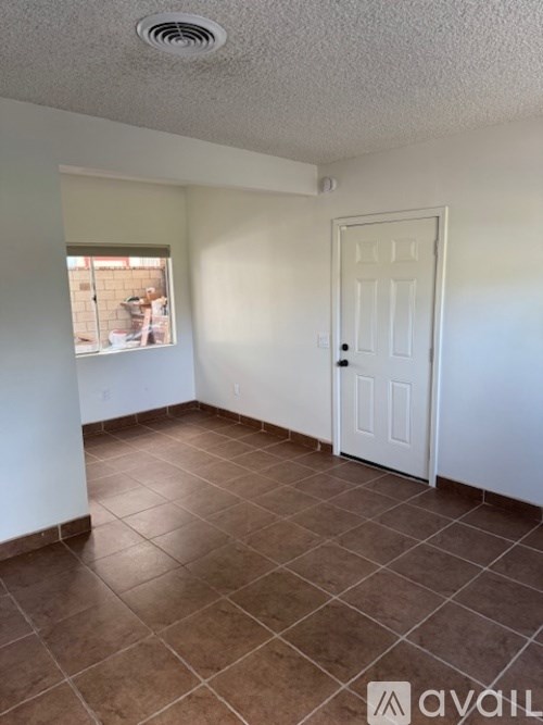 A room with a white door and brown tile flooring.