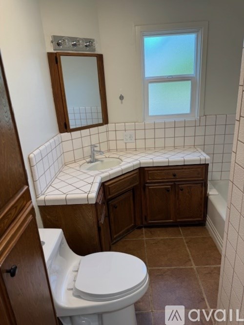 A bathroom with a toilet, sink, and mirror.