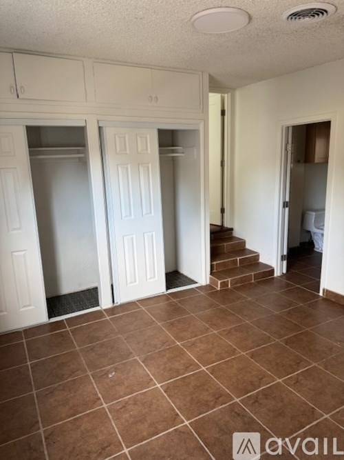 A kitchen with white cabinets and a brown tile floor.