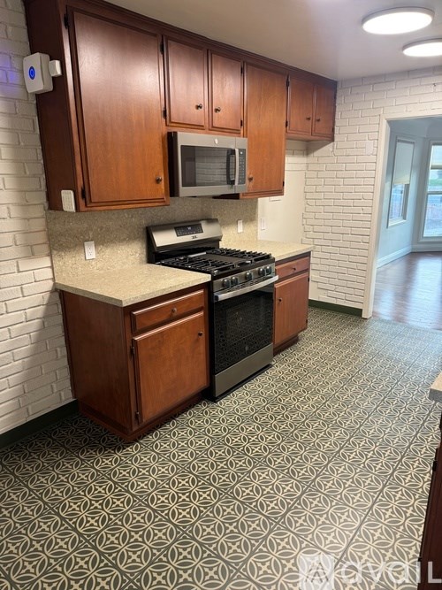 A kitchen with a black stove top oven and a microwave above it.