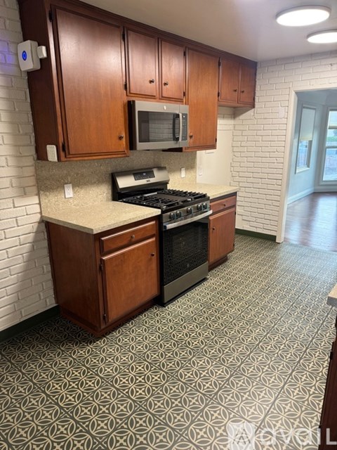 A kitchen with a black stove top oven and a microwave above it.