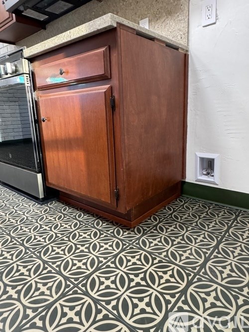 A wooden cabinet with a door is in the middle of a tiled floor.