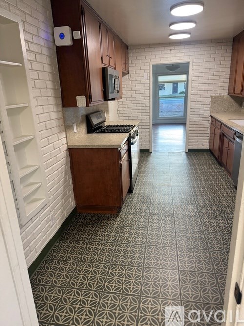 A long hallway with a patterned floor and a door at the end.