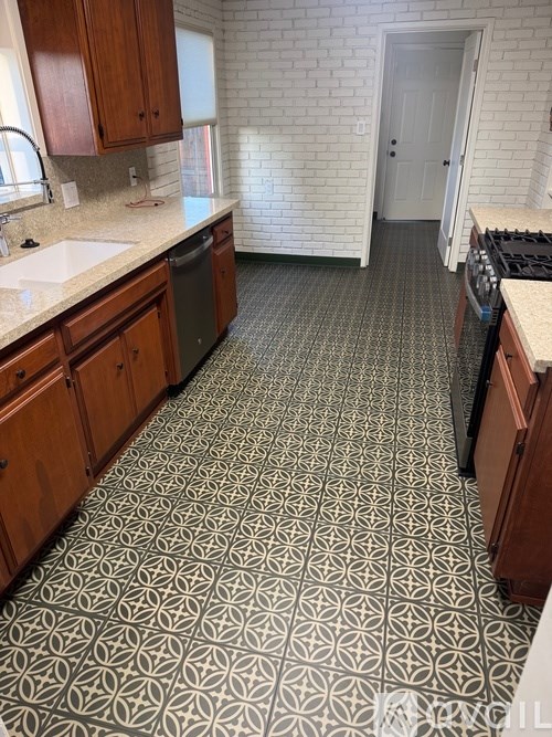 A kitchen with a patterned floor and wooden cabinets.