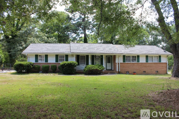 A green and white house with a tree in front.