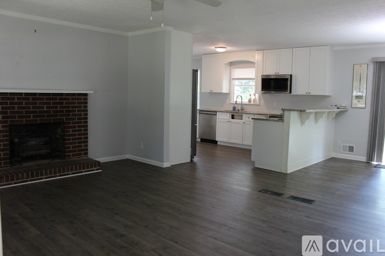 A living room with a fireplace and a kitchen area in the background.