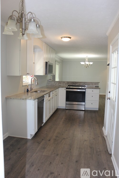 A kitchen with white cabinets and a wooden floor.