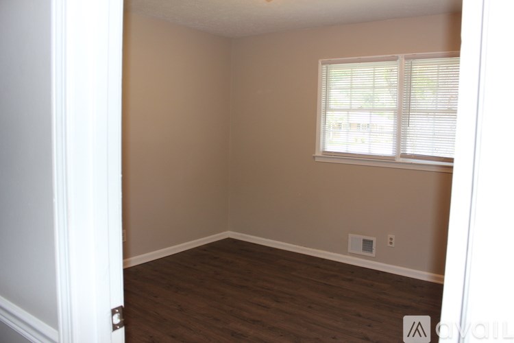 A room with a window and wooden floors.