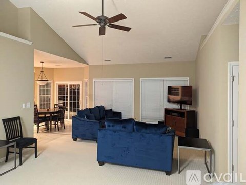 A living room with a blue couch and a ceiling fan.