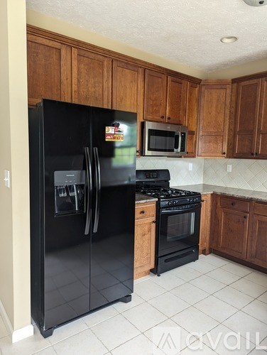 A kitchen with a black fridge, stove and microwave.