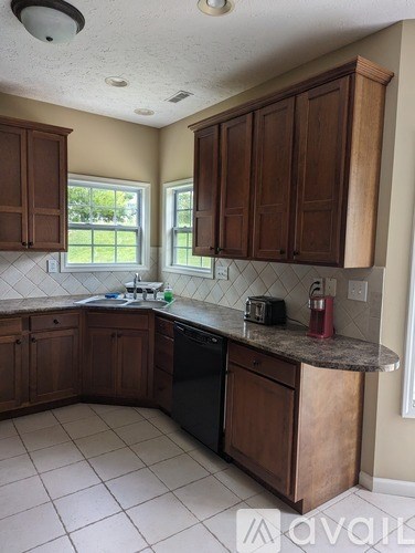 A kitchen with brown cabinets and a black dishwasher.