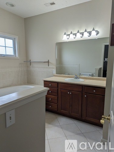 A bathroom with a white tub, sink, and brown cabinets.
