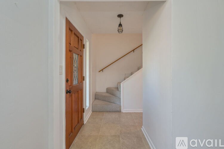 A hallway with a wooden door and a staircase.