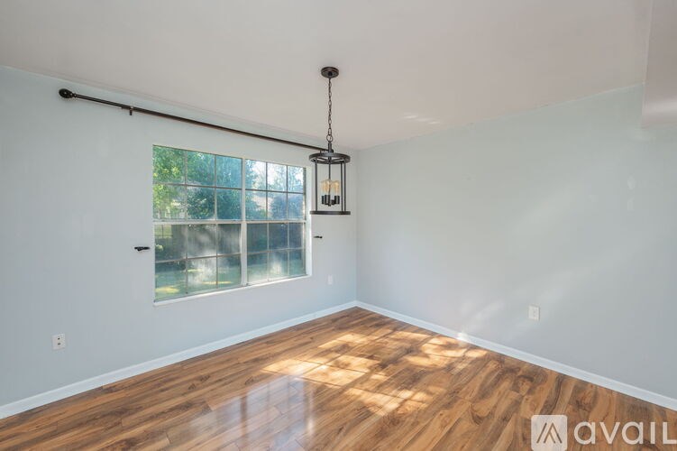 A room with wooden floors and a window with a view of trees.