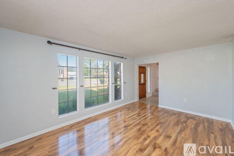 A room with wooden floors and white walls, featuring a sliding glass door.