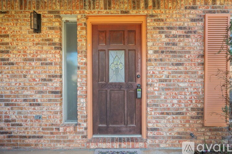 A brown door with a glass panel is set in a brick wall.