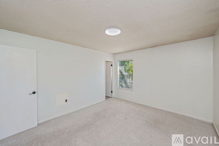 A room with a carpeted floor and a window with blinds.