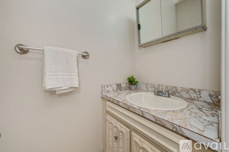 A white towel hangs on a silver towel rack in a bathroom.
