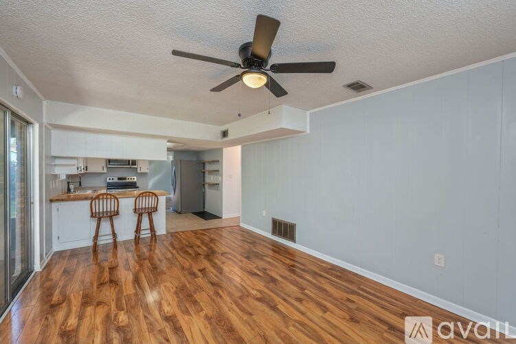 A room with a ceiling fan and wooden flooring.