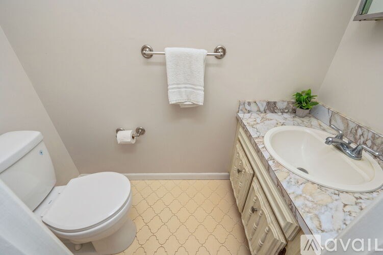 A bathroom with a toilet, sink, and towel rack.