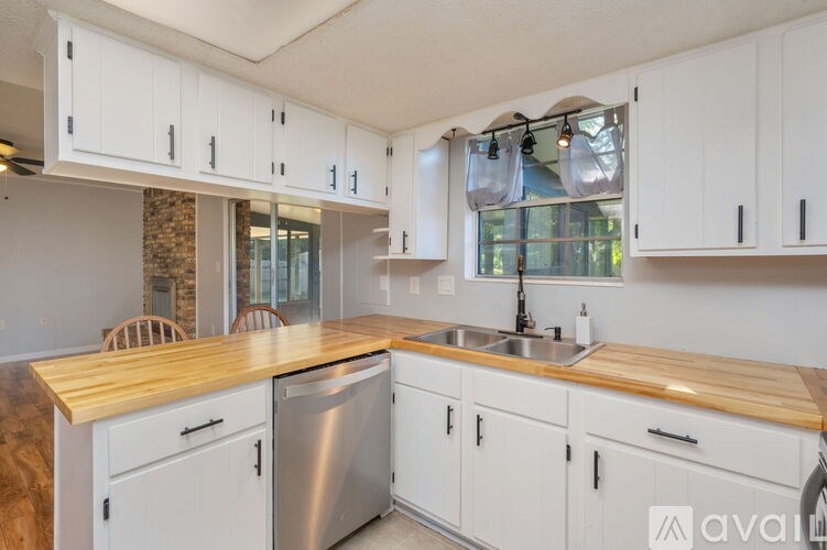A kitchen with white cabinets and a wooden countertop.
