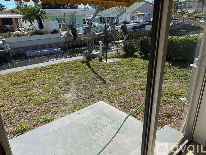 A view from a window looking out to a lawn and a body of water.