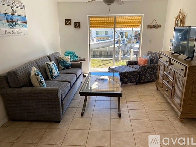 A living room with a grey couch and a glass coffee table.