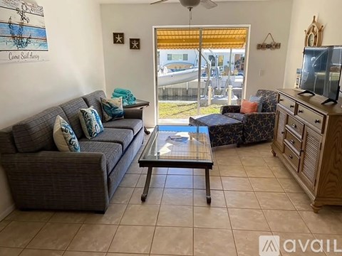 A living room with a grey couch and a glass coffee table.