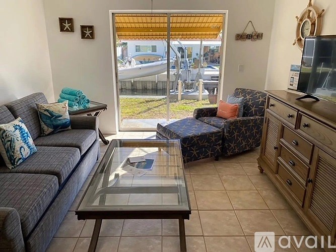 A living room with a grey couch, a glass coffee table, and a television.