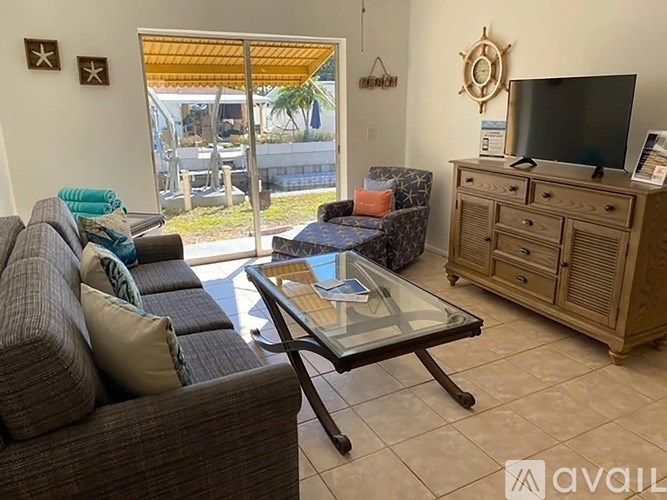 A living room with a couch, a glass table, and a television.