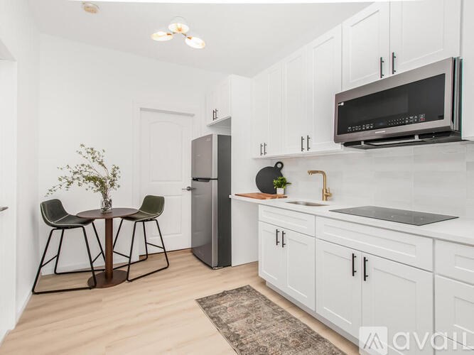 A kitchen with white cabinets and a black fridge.