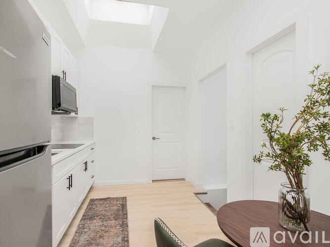 A kitchen with white cabinets and a black microwave.