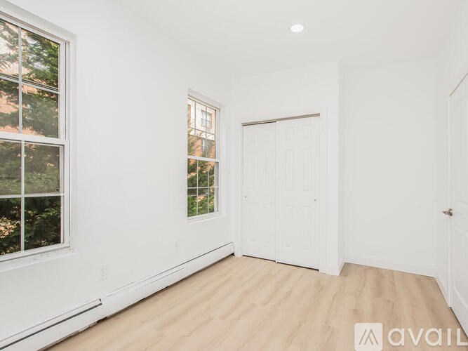 A room with a white door and a window with a view of trees.