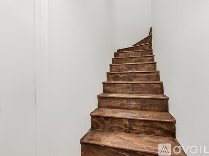 A wooden staircase with a white wall on the side.