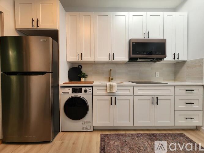 A kitchen with a stainless steel refrigerator, a washing machine, and a microwave.